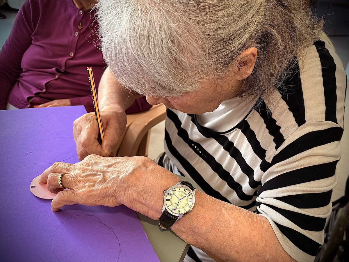 Le mani di un&rsquo;ospite che scrive il proprio ricordo su una foglia di carta viola