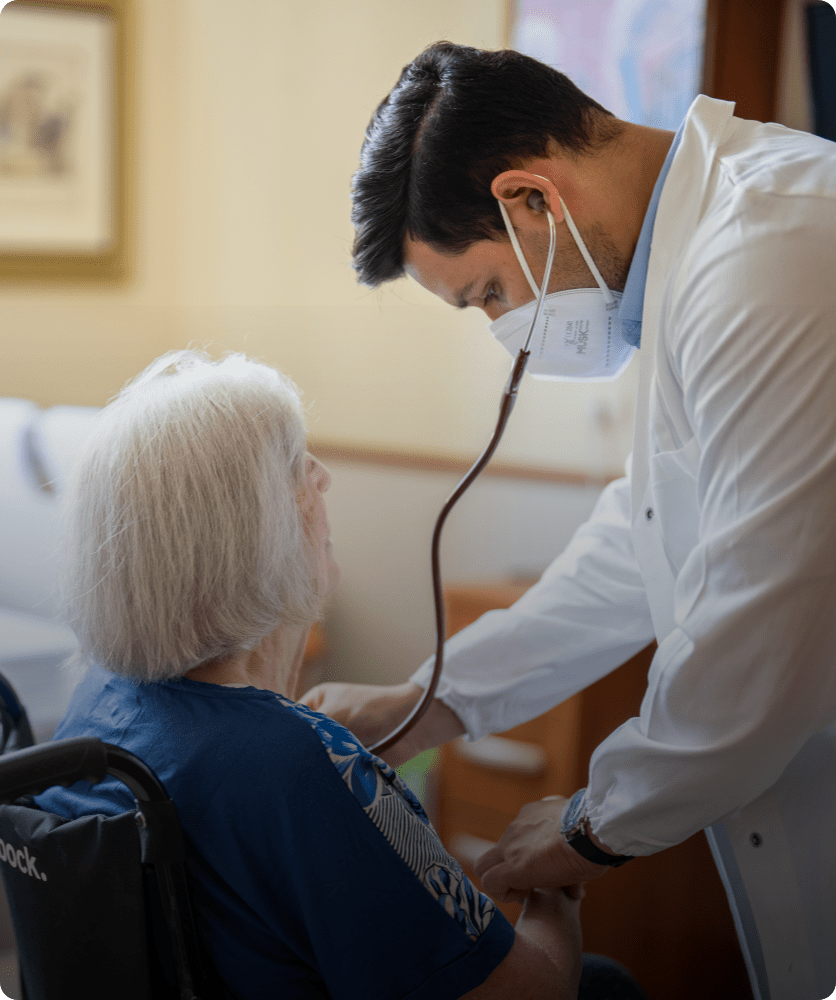 Medico che ausculta un'ospite in sedia a rotelle