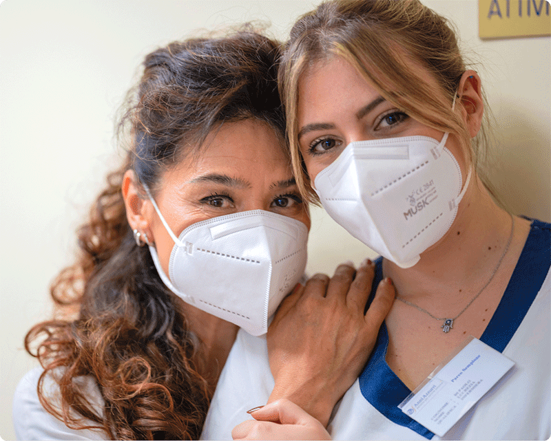 Due operatrici sanitarie sorridenti abbracciate