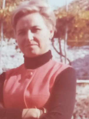 Giovanna a mezzo busto, a braccia conserte, in abito rosso senza maniche.